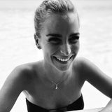 Woman wearing the Orfélie Manon pendant in 18k gold with lemon quartz, standing in a pool. Only the upper body and water reflections are visible.